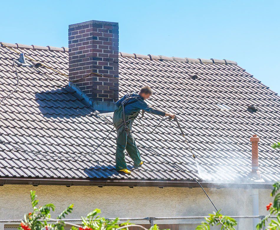 Ouvrier nettoie une toiture à l'aide d'un Kärcher