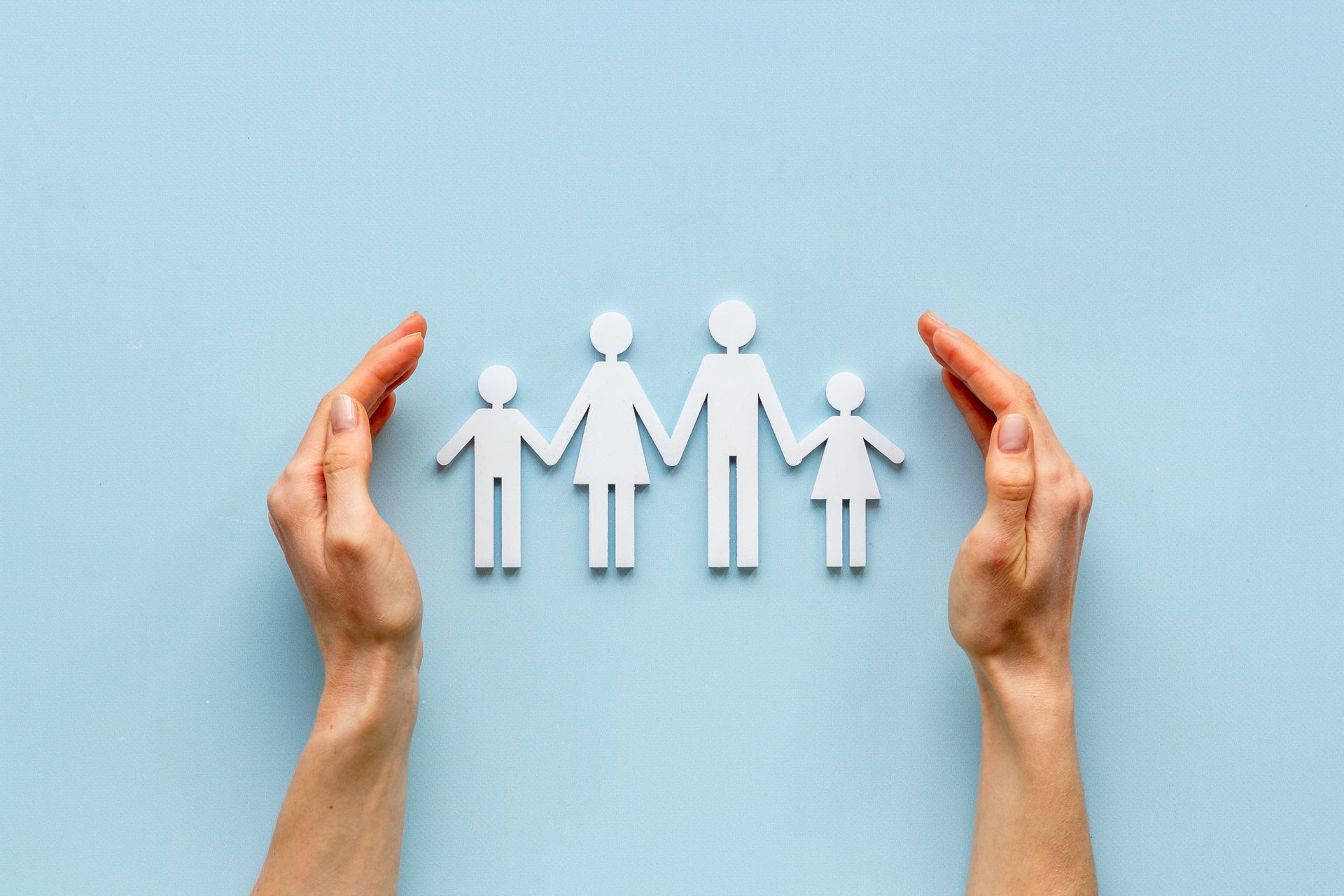 Famille en papier entourée par les mains d'une personne