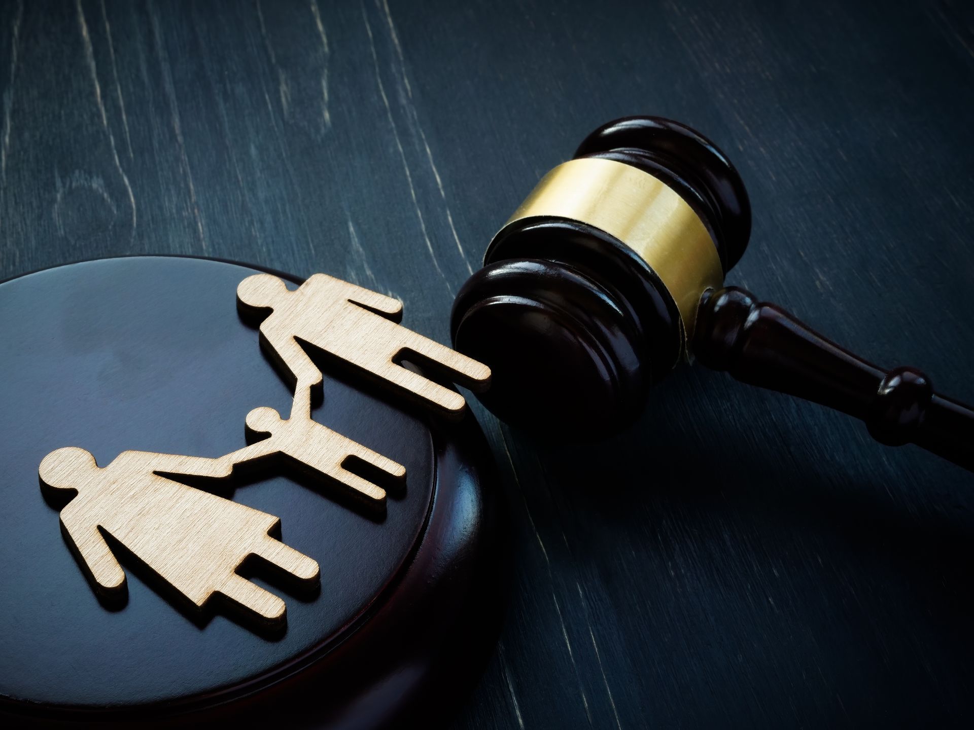 Figurines en bois représentant la famille près d'un marteau de tribunal.