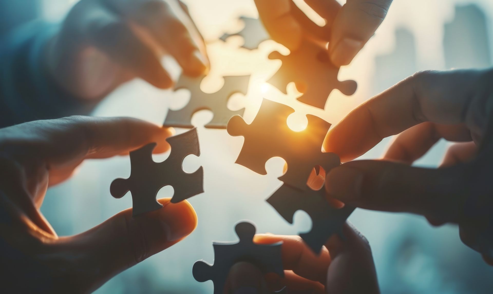 Des mains rapprochant des morceaux de puzzle en contre-jour.