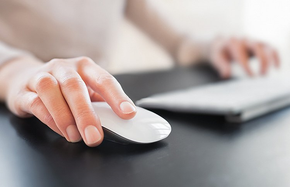 Mains sur une souris et un clavier d’ordinateur blancs.