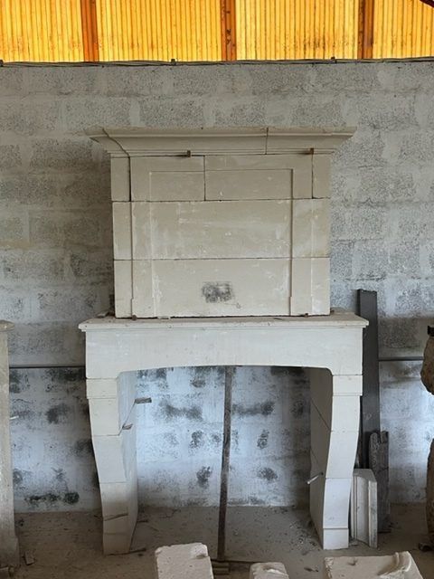 Cheminée en pierre calcaire en cours d'assemblage contre un mur de briques.