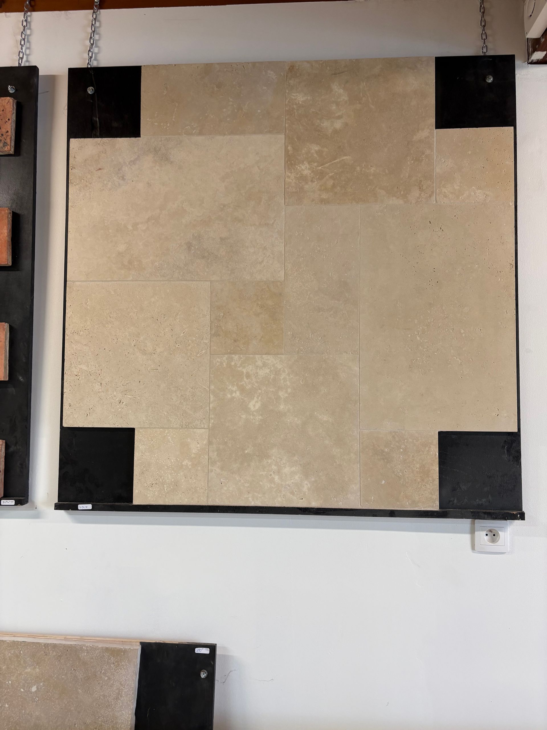 Panneau de carreaux carrés beiges avec supports d'angle noirs, fixé au mur