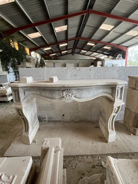 Cheminée en pierre dans un atelier, ornée de détails raffinés et dotée d'un manteau incurvé.