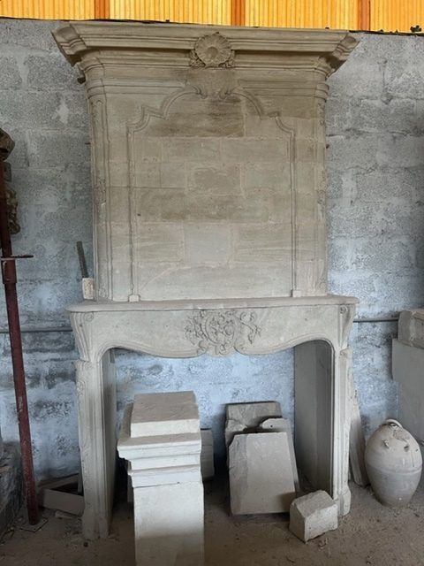 Cheminée en pierre aux détails ornementaux, inachevée, dans un atelier.