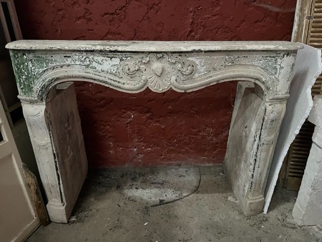 Cheminée ancienne en pierre ornée de sculptures et peinte en vert et blanc patiné.