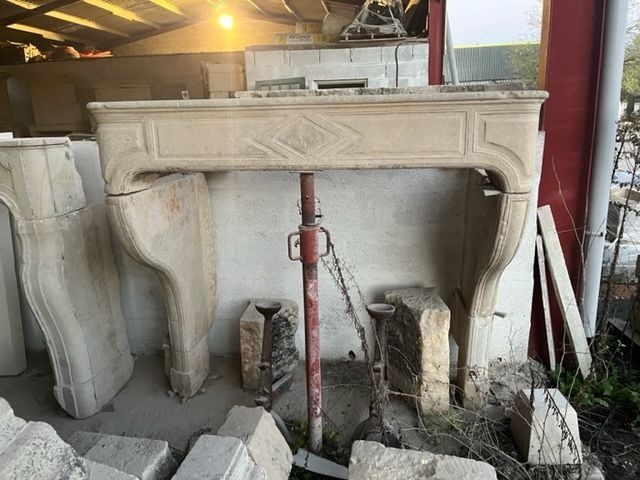 Cheminée en pierre, de couleur beige clair, soutenue par un pilier rouge. D'autres éléments en pierre se trouvent à proximité.