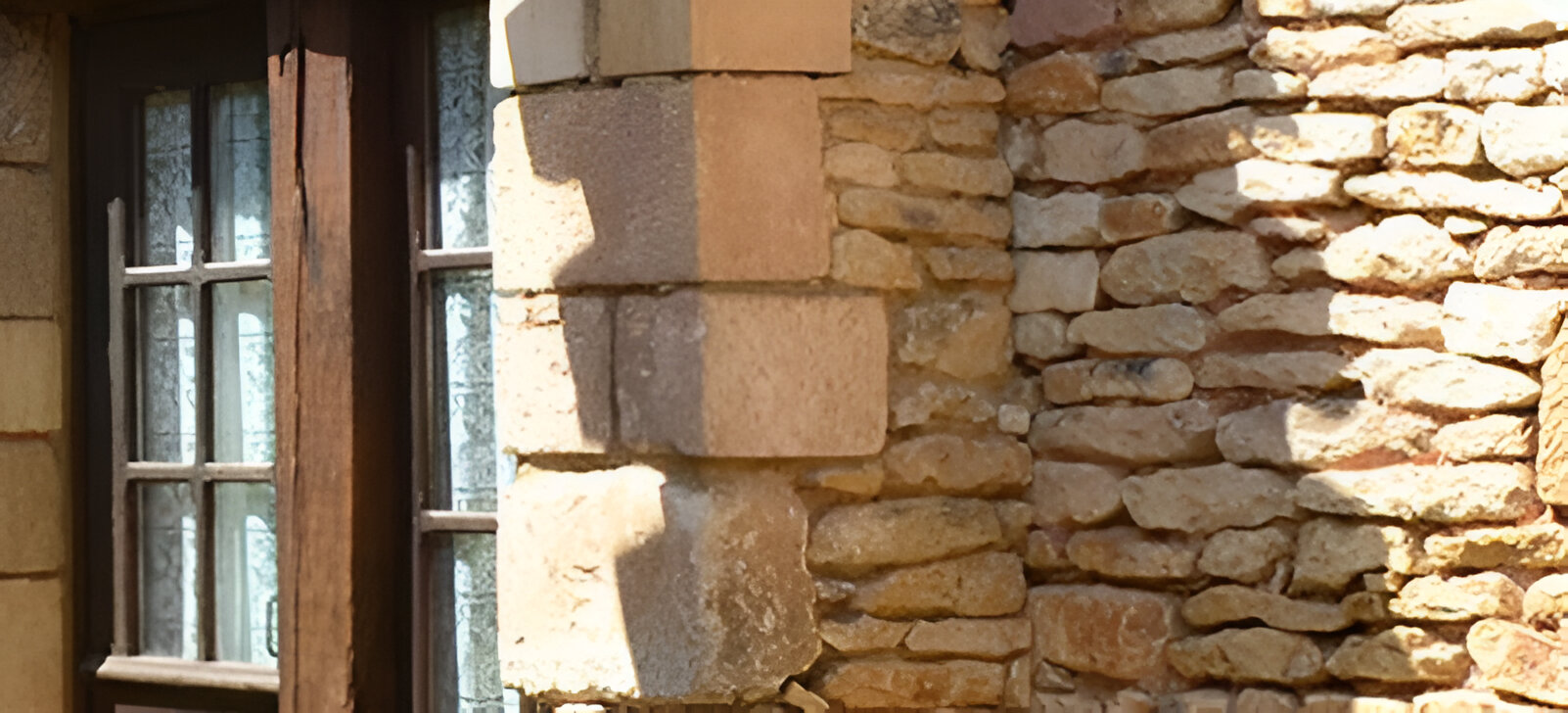Vue extérieure d'un bâtiment en pierre avec une fenêtre et un angle.