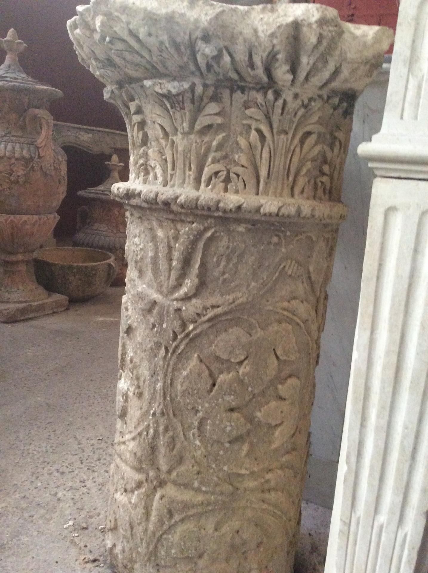 Des colonnes de pierre longent un mur érodé, à côté d'un chemin de jardin et d'un cours d'eau.