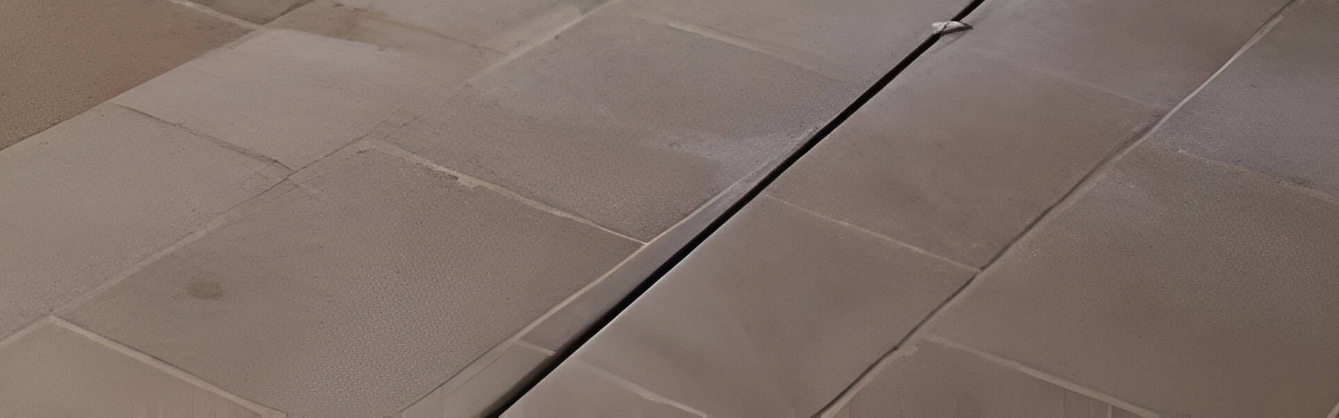 Gros plan sur un sol carrelé marron avec une ligne sombre en diagonale.