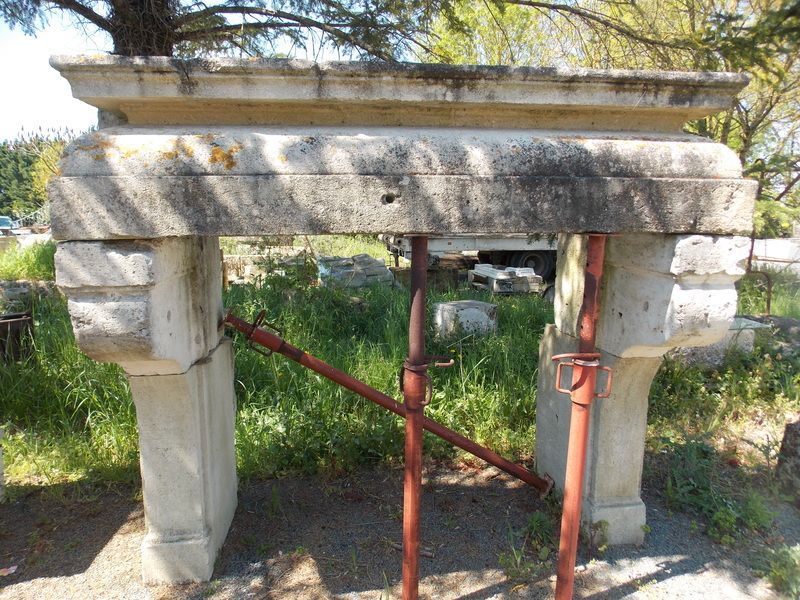 Cheminée en pierre soutenue par des supports métalliques à l'extérieur.