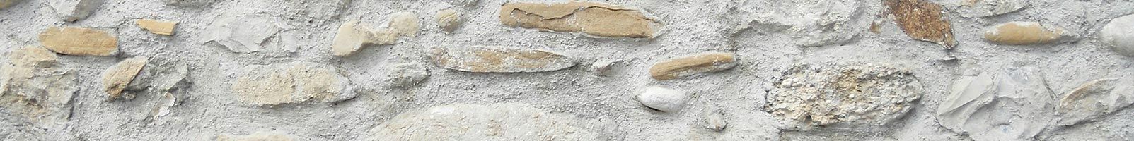 Gros plan sur un mur de pierres patinées par le temps, composé de pierres beiges de tailles variées, enchâssées dans un mortier gris.