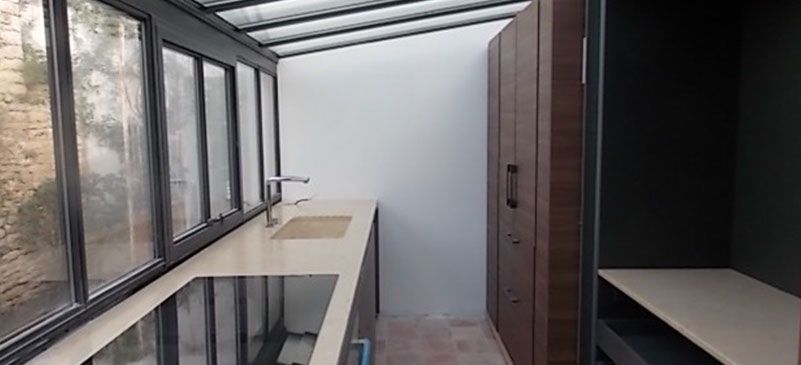 Cuisine moderne avec placards foncés, comptoir en pierre, évier et grandes fenêtres.