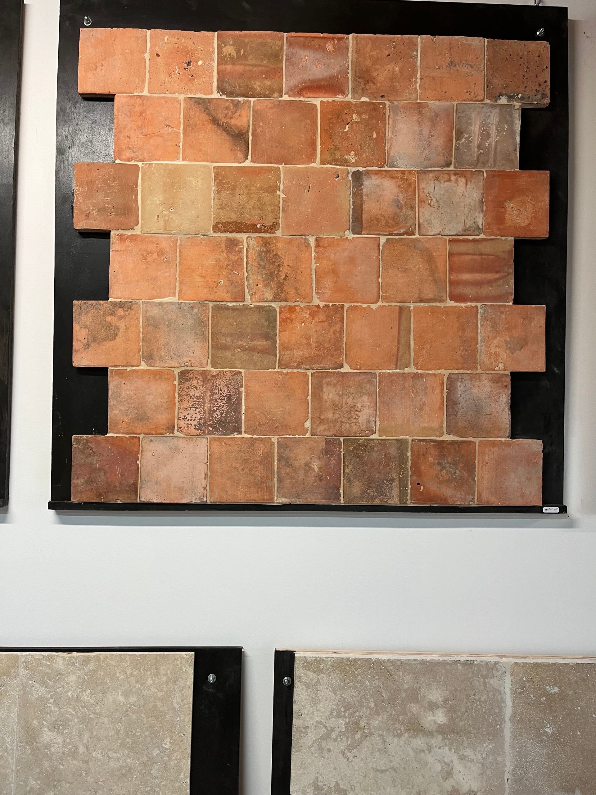 Présentation d'échantillons de carreaux carrés, dont une mosaïque de carreaux de pierre beige et orange.
