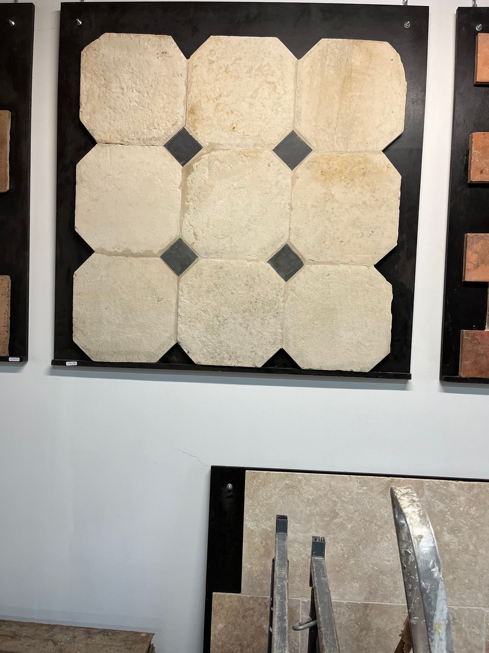 Présentation d'échantillons de carreaux hexagonaux crème avec des accents de losanges noirs sur un mur