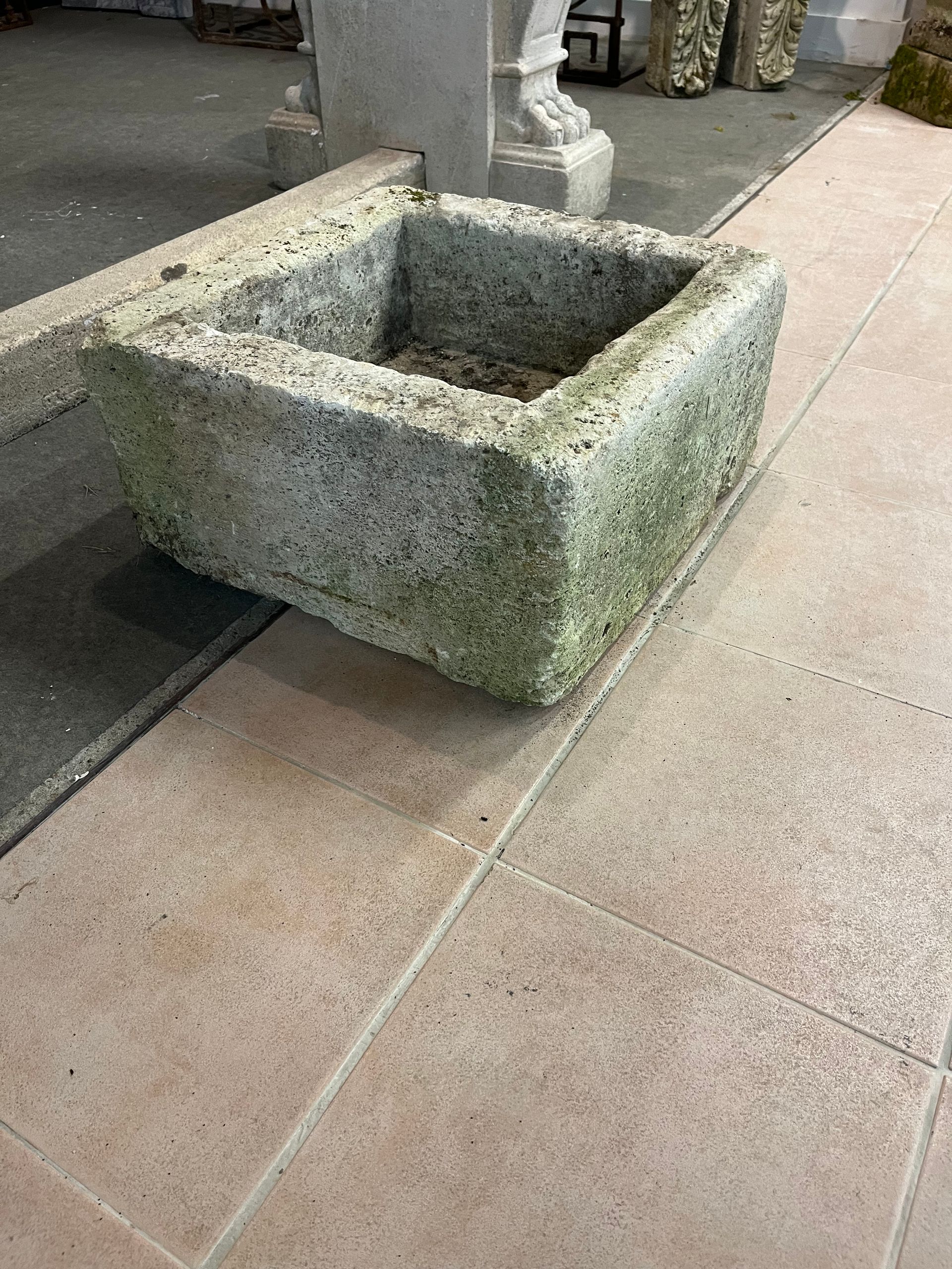 Jardinière en pierre au bord d'un trottoir, vide et usée par les intempéries.