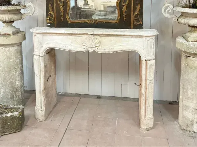 Console blanche sculptée entre deux jardinières en pierre dans un intérieur rustique.