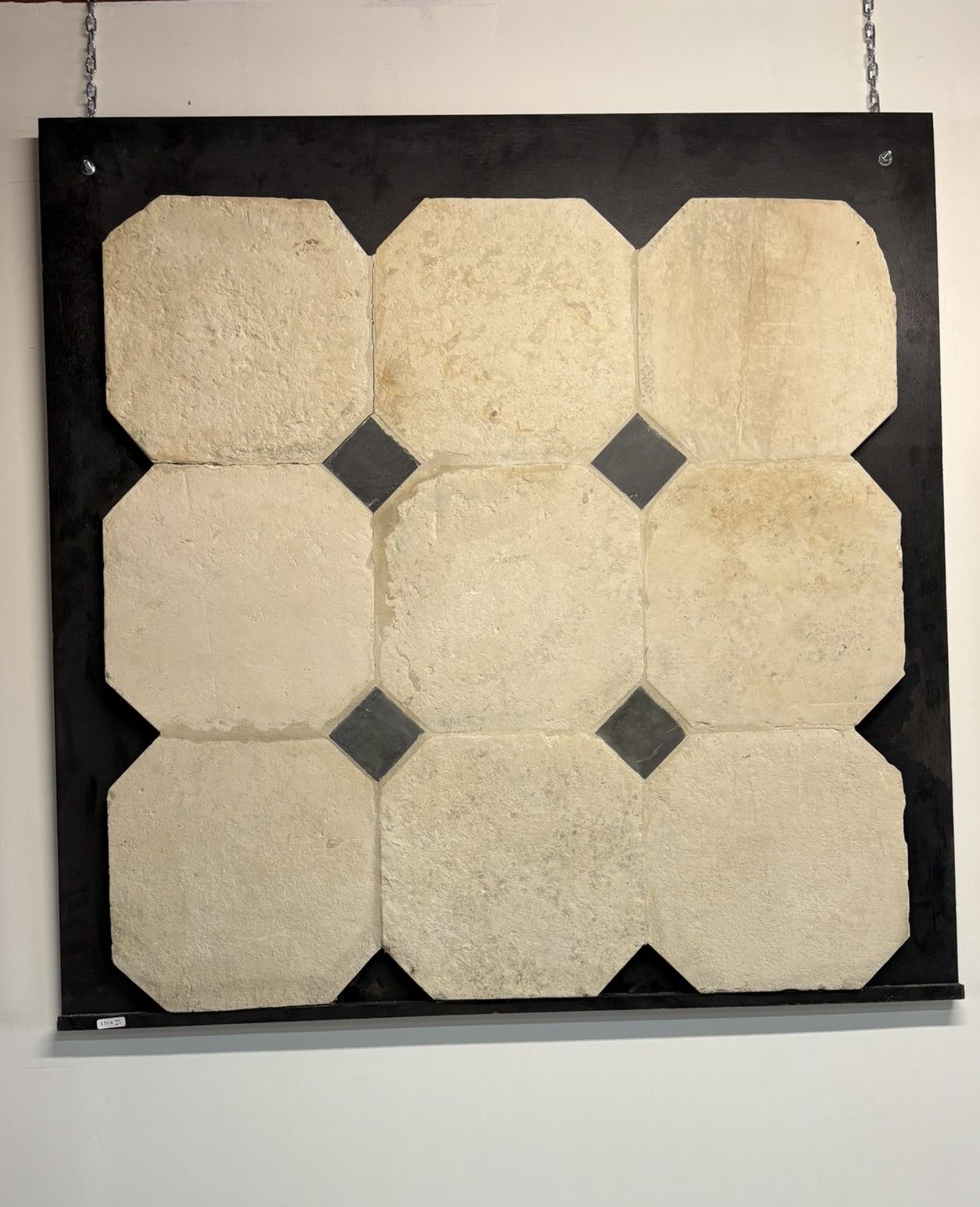 Présentoir encadré de noir, composé de neuf carreaux octogonaux beiges disposés en grille 3x3