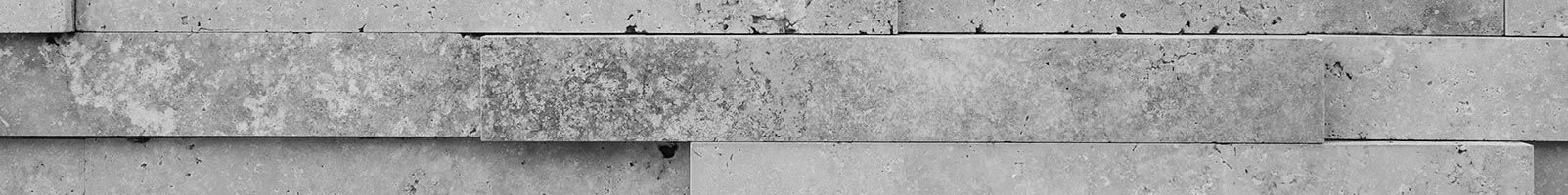 Des blocs de béton rectangulaires gris forment un mur texturé horizontal.