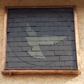 Mosaïque de colombe en ardoise dans un carré encadré de cuivre.