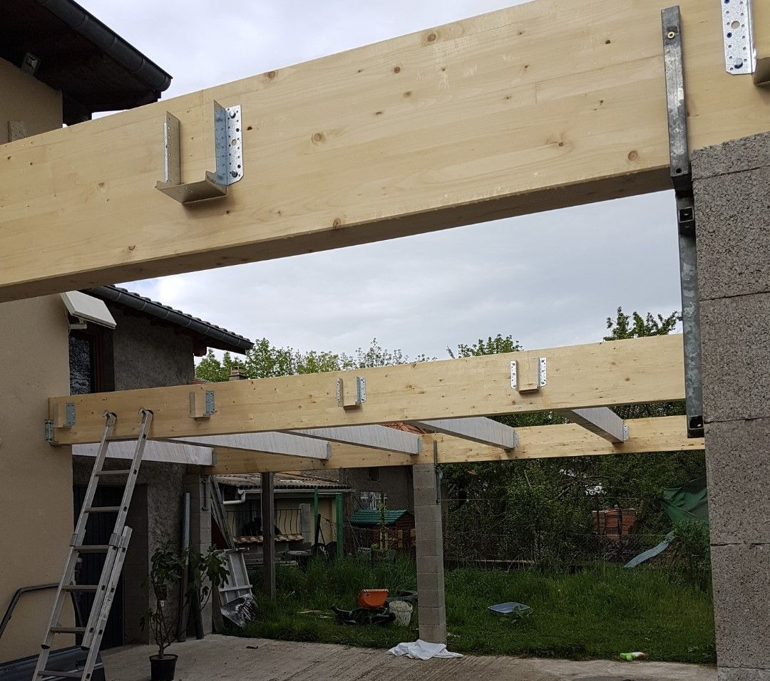 Poutres et solives en bois avec supports métalliques, faisant partie d'une structure extérieure en construction.