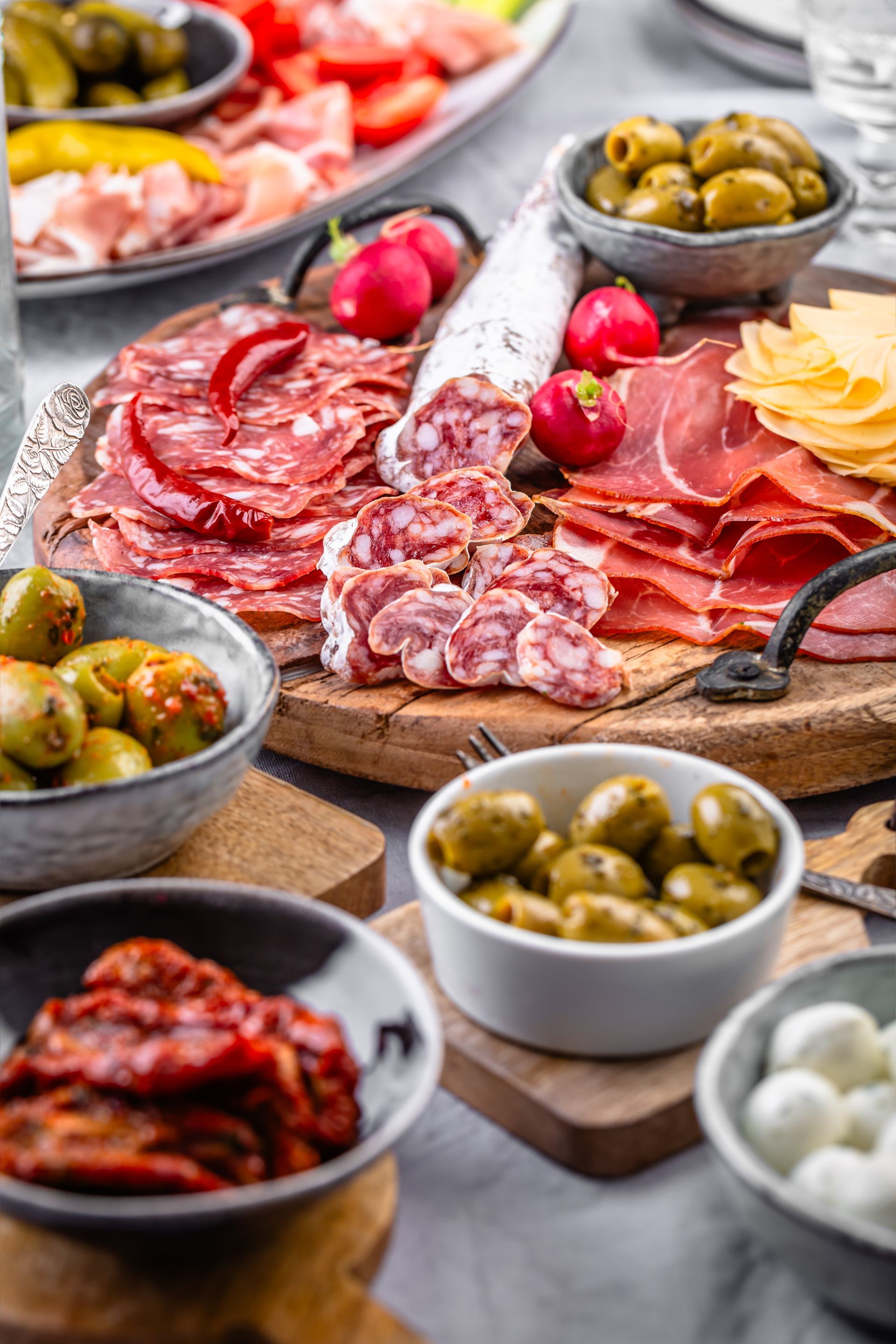 Planche de charcuterie avec salami, prosciutto, olives, fromage et tomates.