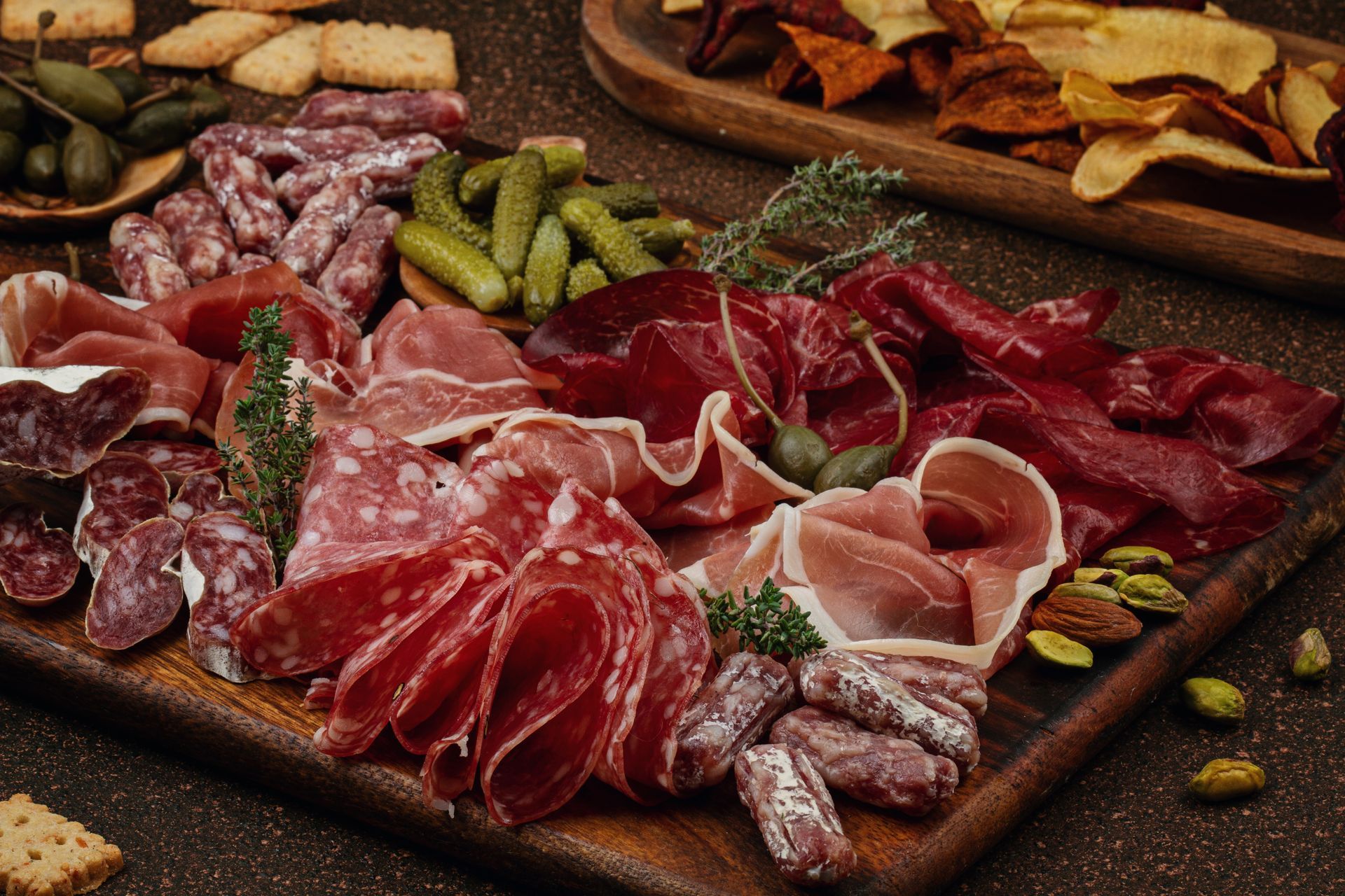 Planche de charcuterie avec viandes variées, cornichons, craquelins et noix.