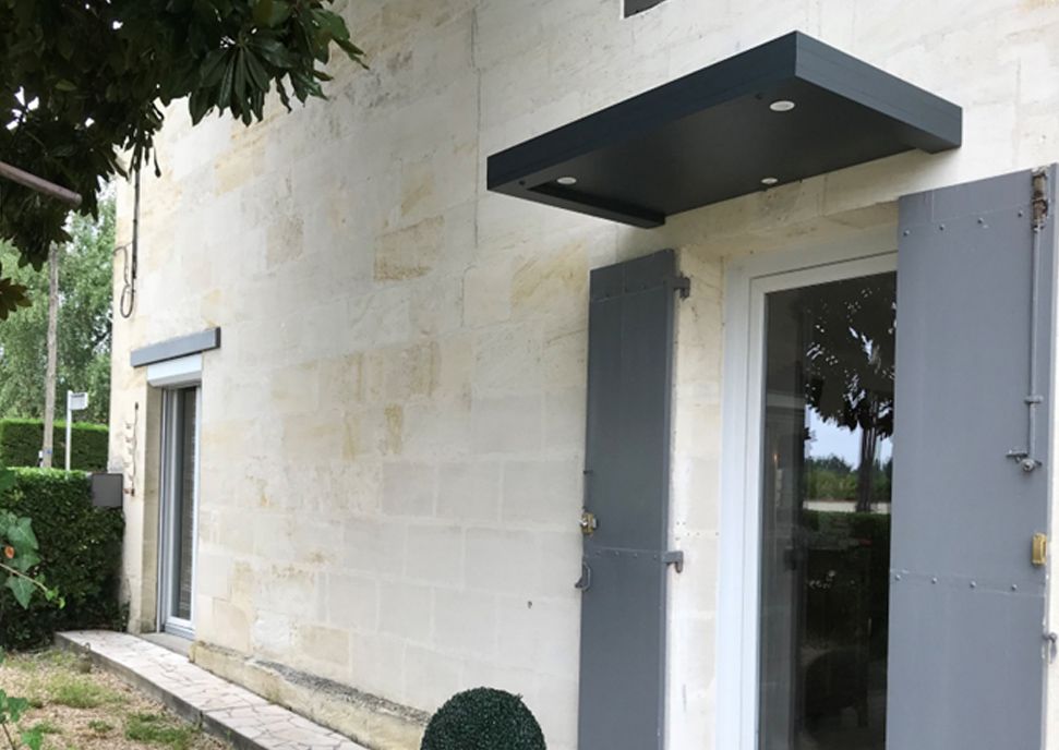 Porte d'entrée d'une maison avec une marquise en aluminium