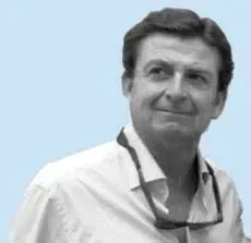 Hombre con camisa blanca sonriendo, con gafas colgando alrededor de su cuello, sobre un fondo azul claro.