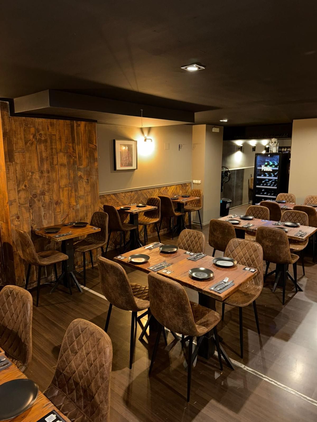 Un comedor con mesas y sillas y una planta en maceta sobre la mesa.