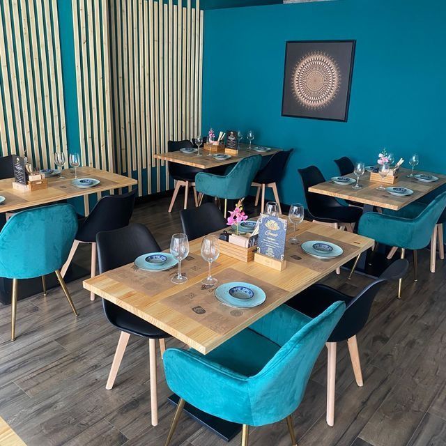 Un restaurante lleno de mesas y sillas con platos y vasos sobre ellas.