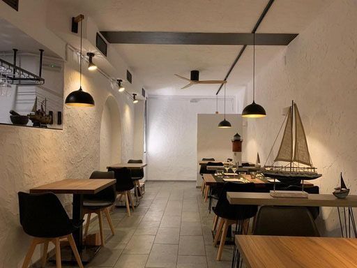 Un restaurante con mesas y sillas y un velero en la pared.