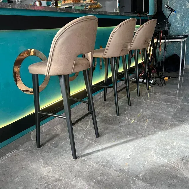 Una fila de taburetes de bar están alineados frente a un mostrador azul.