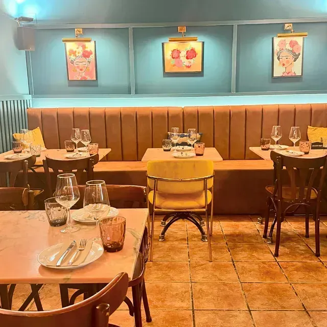 Un restaurante lleno de mesas y sillas y copas de vino.