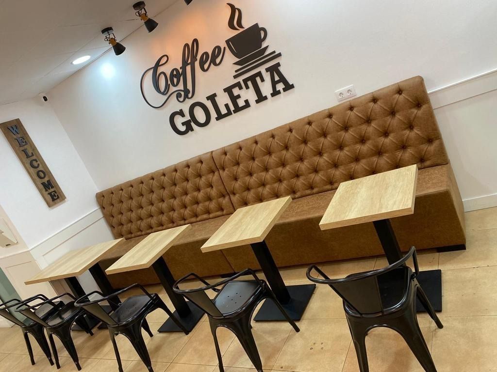 Una cafetería con mesas y sillas y un cartel que dice café goleta