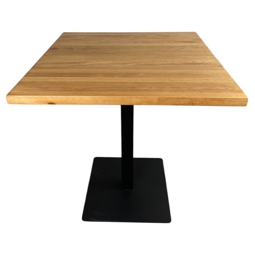 Una mesa de madera con una base negra sobre un fondo blanco