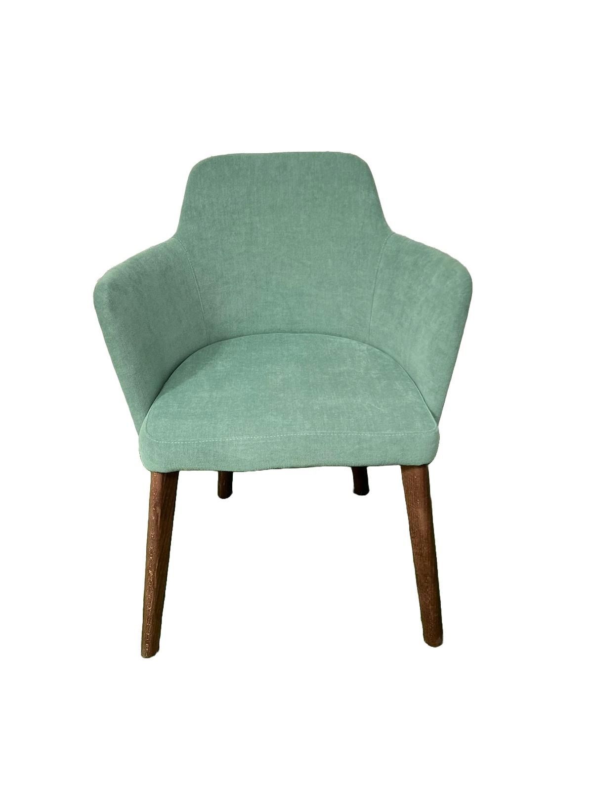 Una silla verde con patas de madera sobre un fondo blanco.