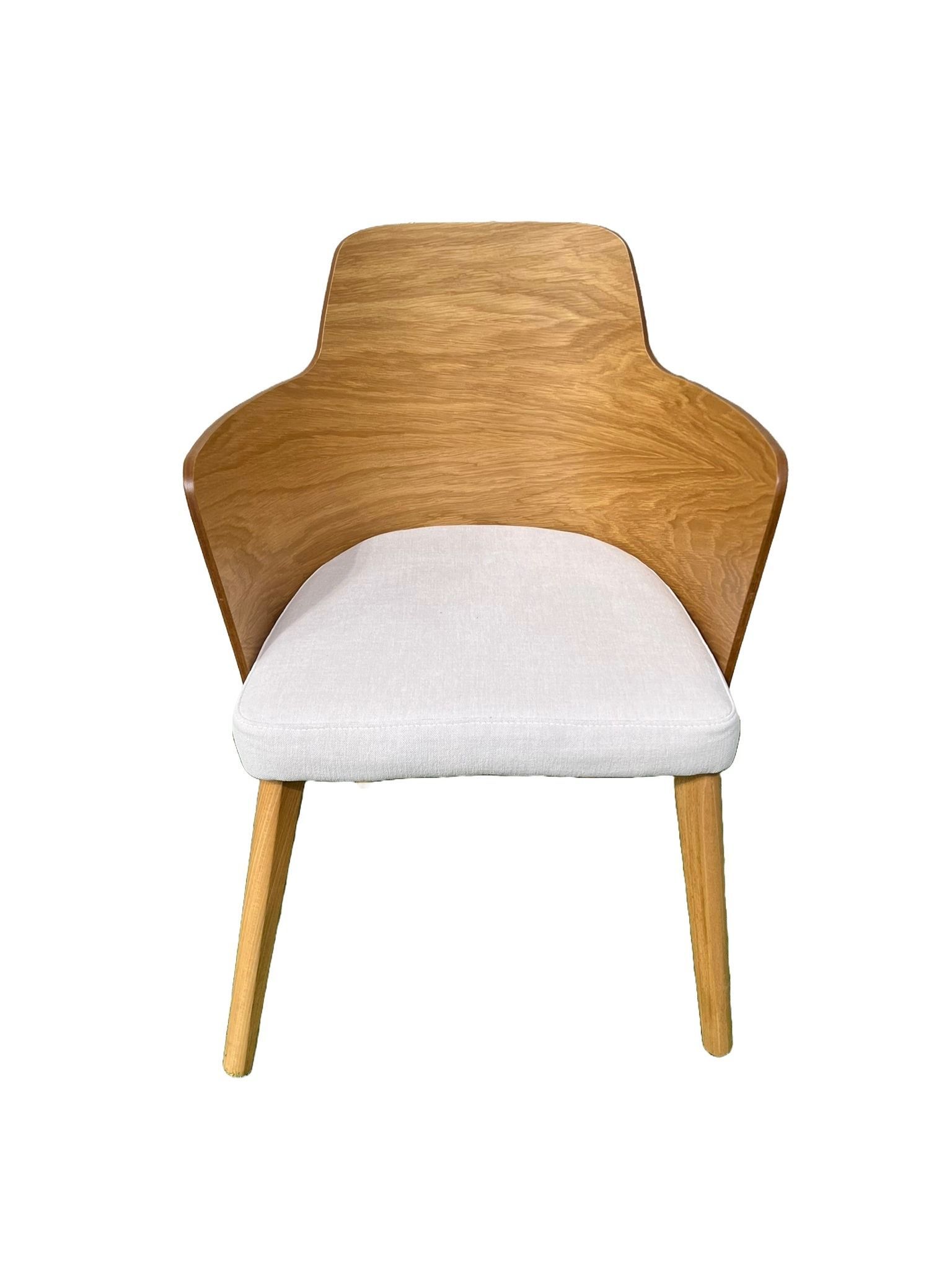 Una silla de madera con un cojín blanco sobre un fondo blanco.
