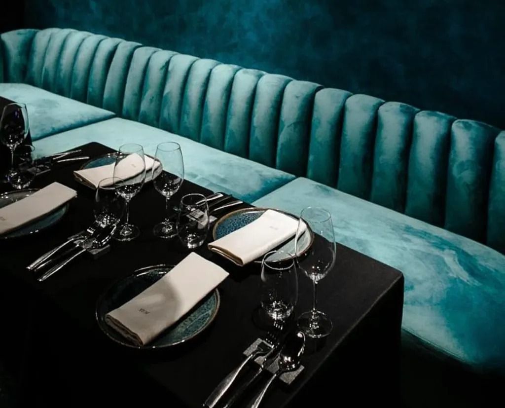 Una mesa con platos, cubiertos y copas de vino en un restaurante.