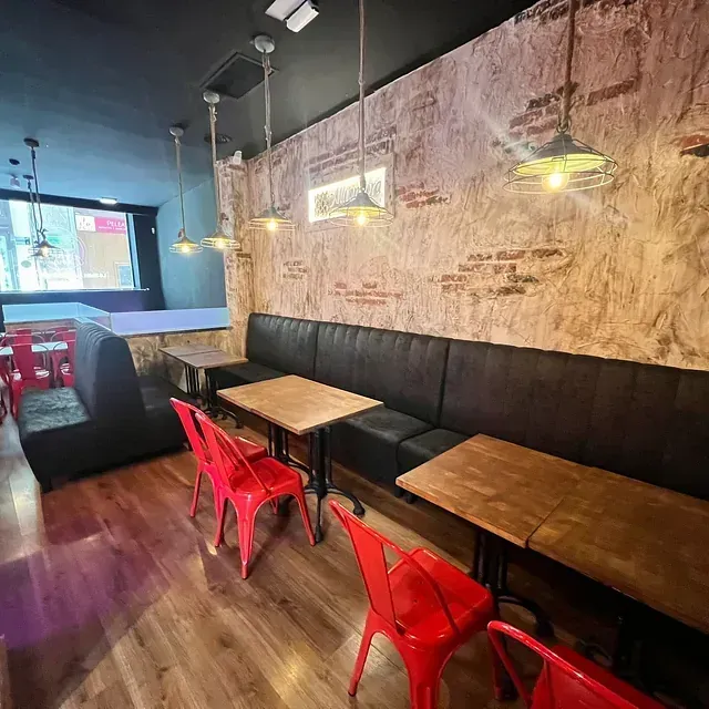 Un restaurante con mesas de madera y sillas rojas.