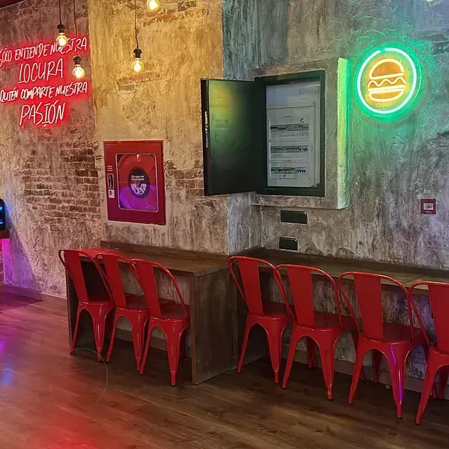 Una fila de sillas rojas están alineadas junto a una mesa en un restaurante.