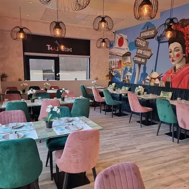 Un restaurante con mesas y sillas y un mural en la pared que dice Bangkok.