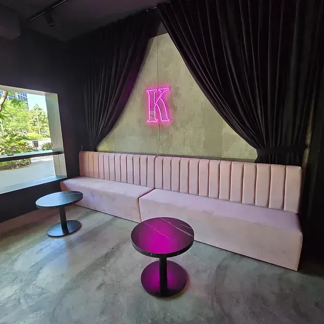 Una habitación con un sofá y dos mesas y un letrero de neón que dice k