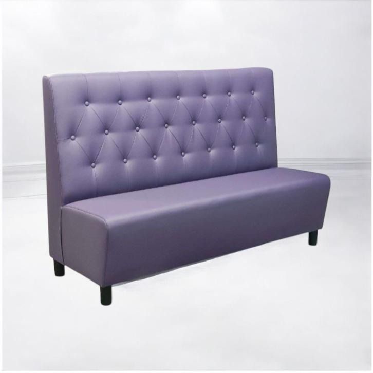 Un sofá verde con mechones acolchados se encuentra frente a una pared blanca.