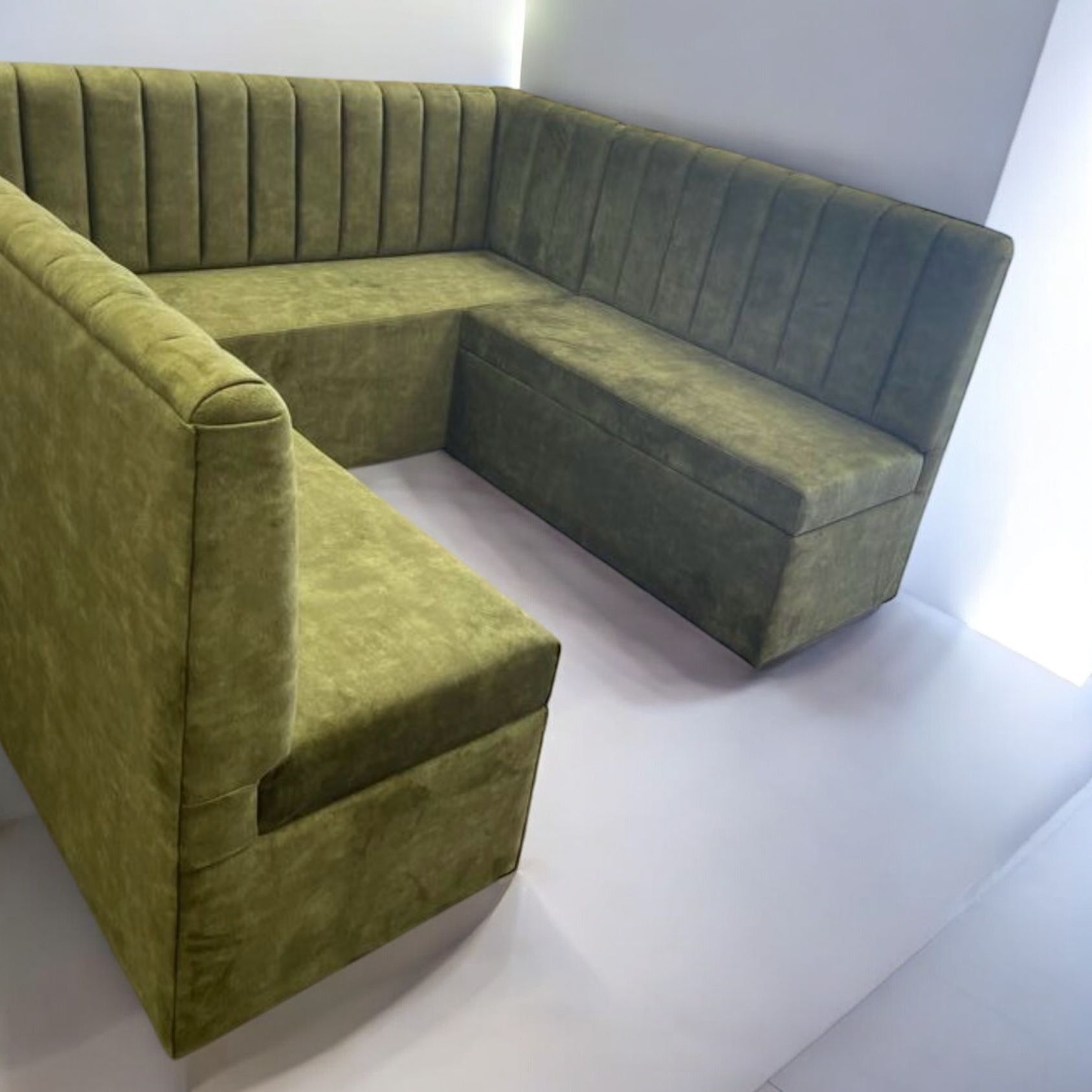 Un sofá seccional verde con una caja de almacenamiento debajo.