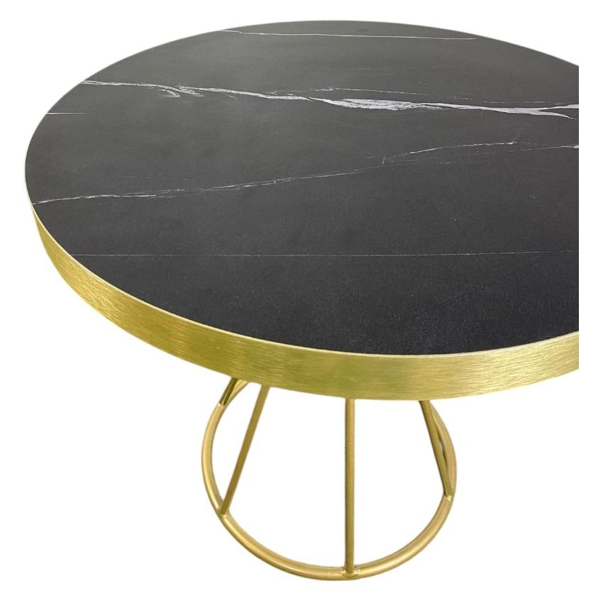 Una mesa redonda con tapa de mármol negro y marco dorado.