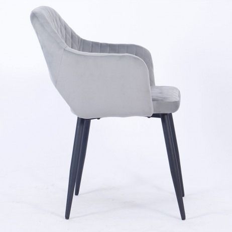 Una silla de terciopelo gris con patas negras sobre un fondo blanco.