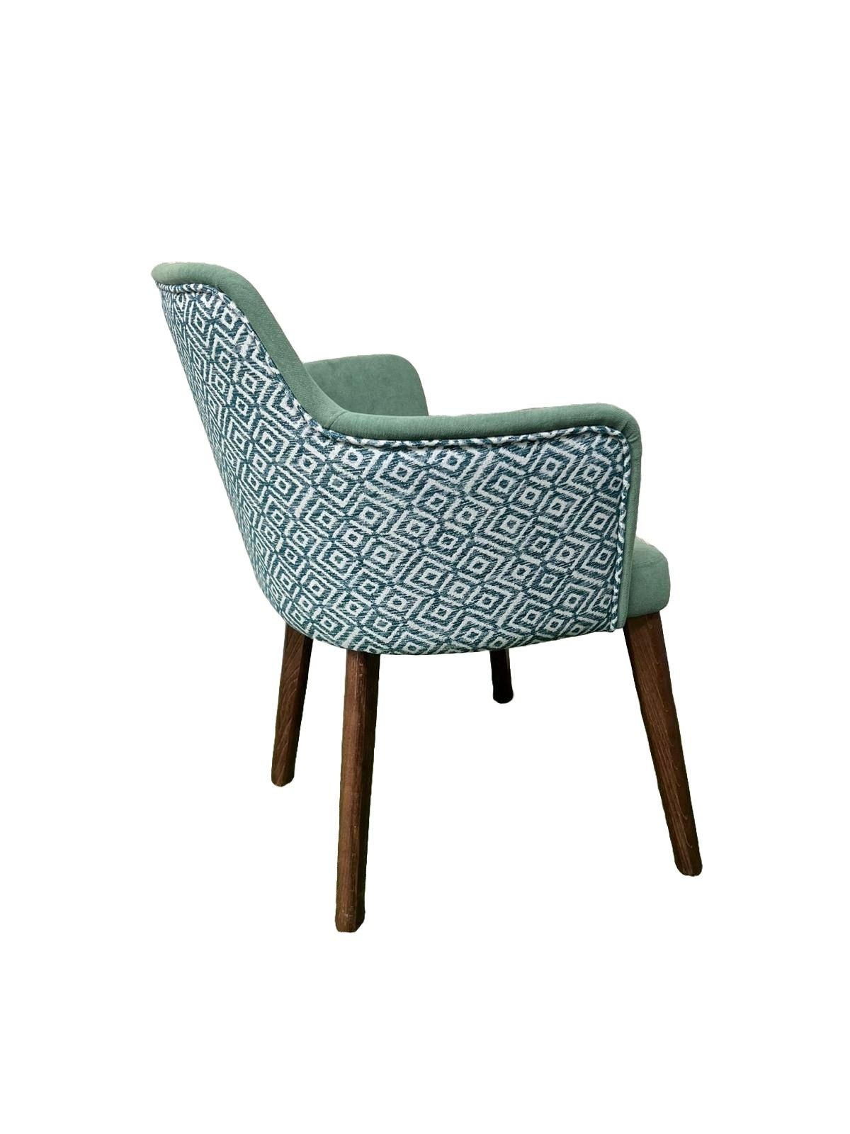 Una silla verde con patas de madera sobre un fondo blanco.