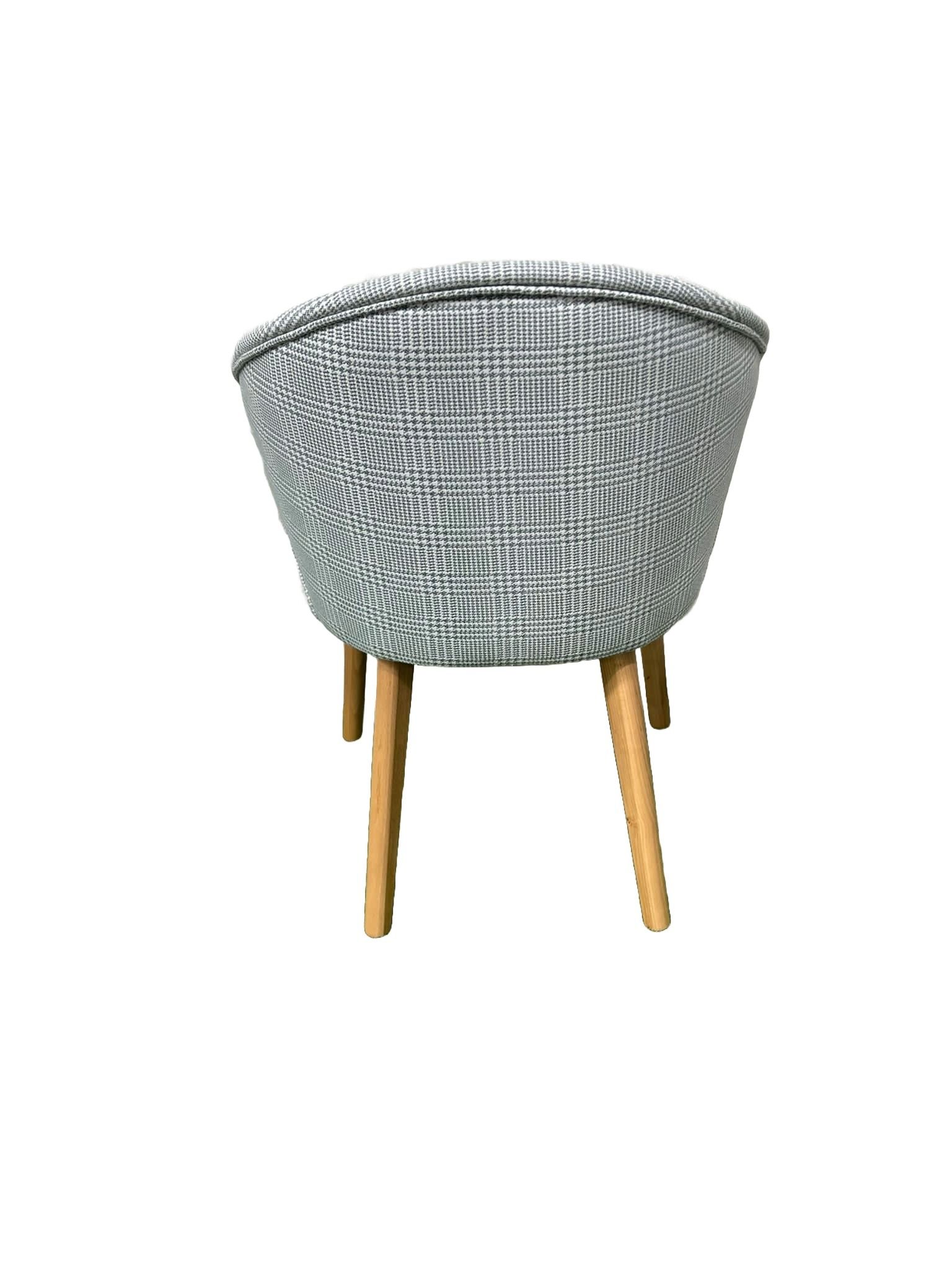 Una silla de mimbre con un cojín azul y patas de madera sobre un fondo blanco.