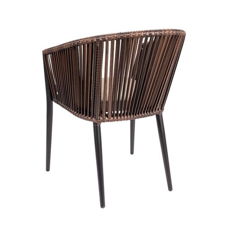 Una silla de mimbre con un cojín sobre un fondo blanco.